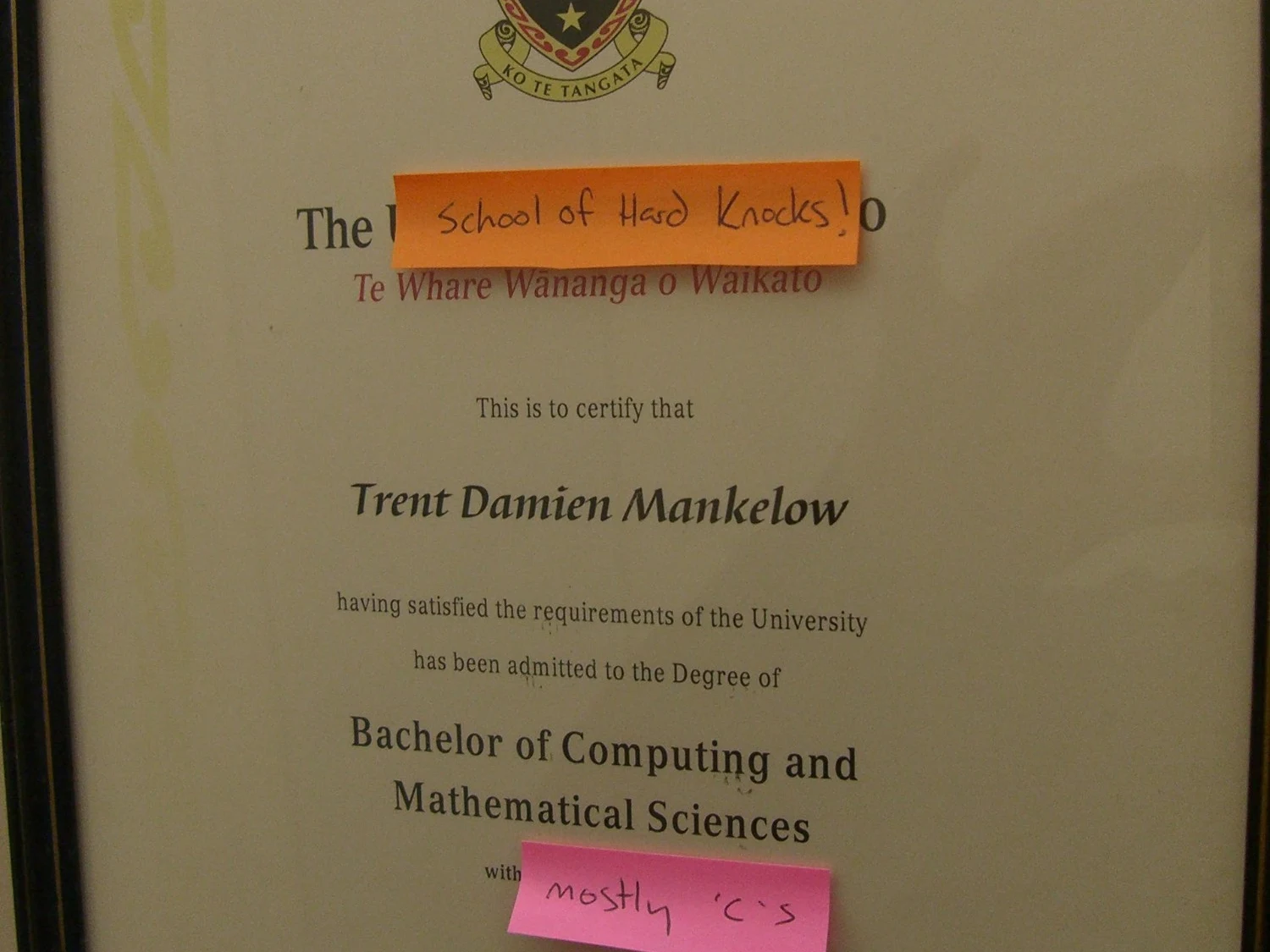 Trent's framed Bachelor of Computing and Mathematical Sciences degree certificate, with joke sticky notes covering 'University' and the grade