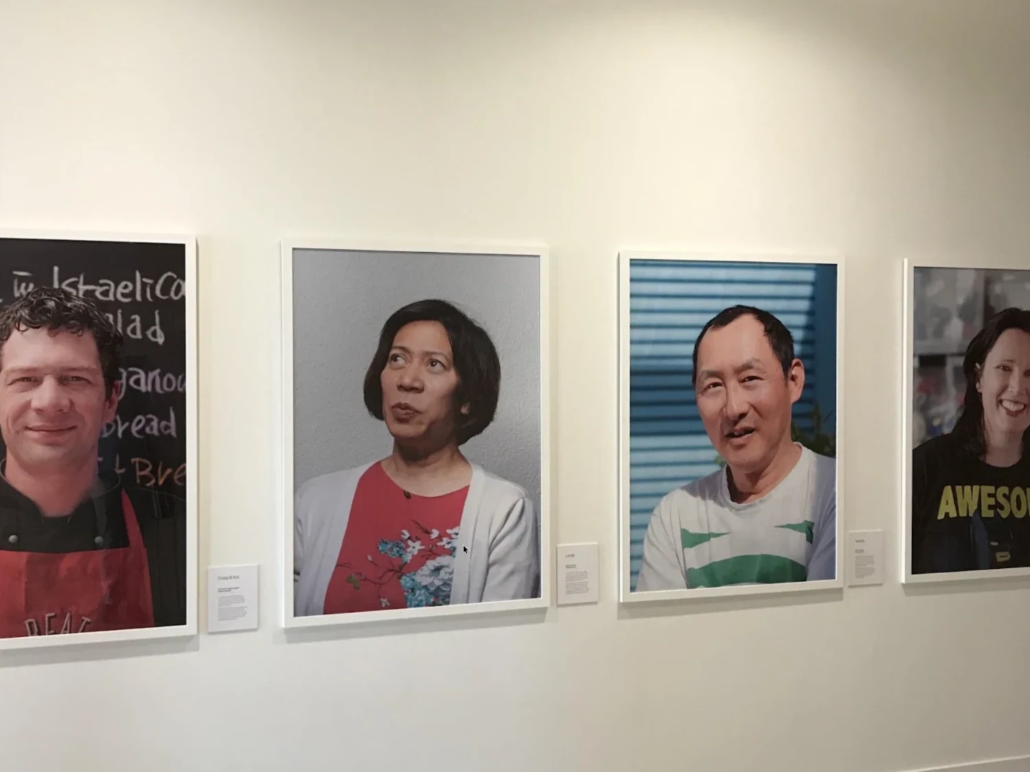 Four framed customer portraits displayed on a gallery wall