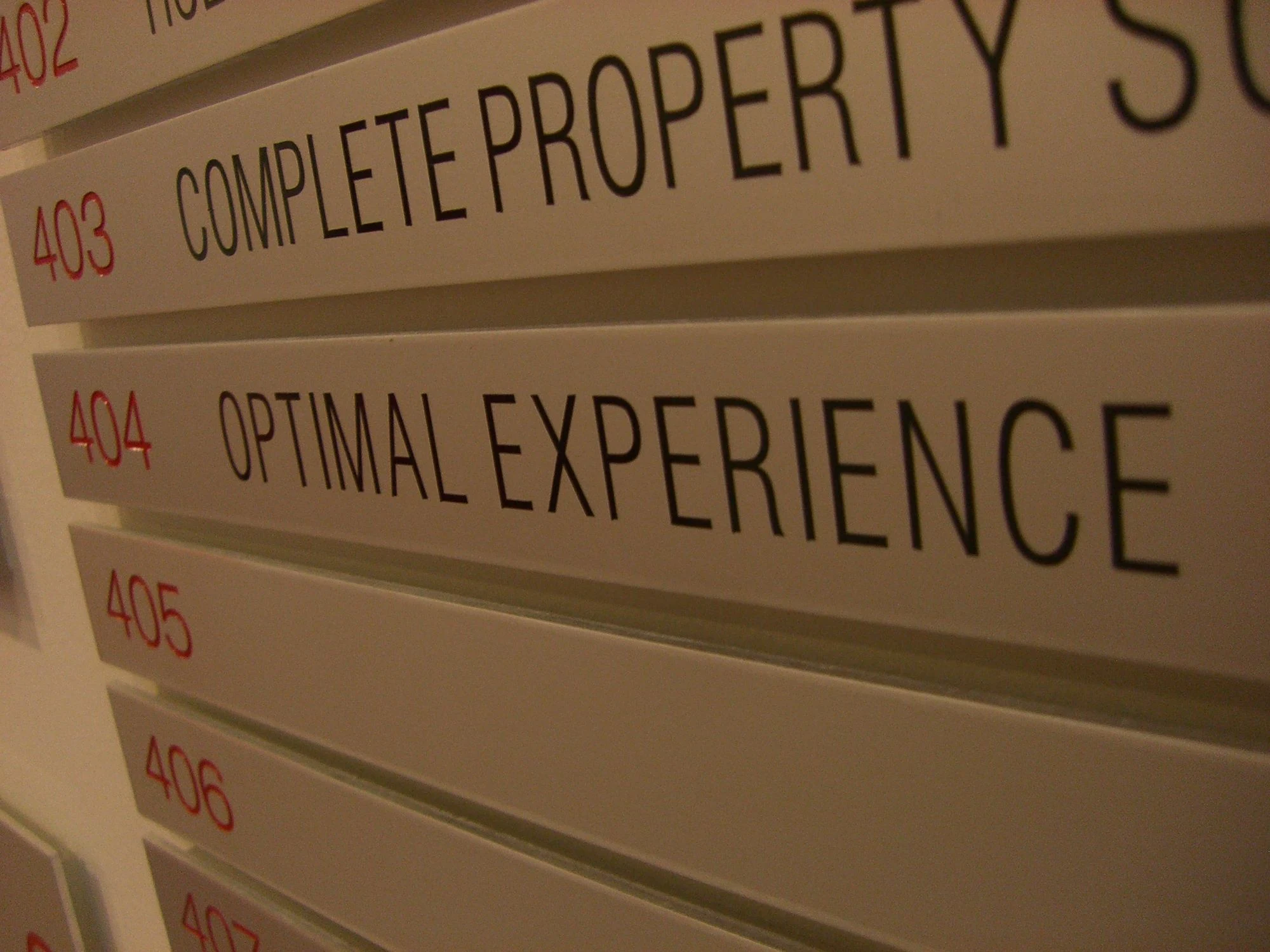 The Optimal Experience directory listing on an office building floor sign in Sydney